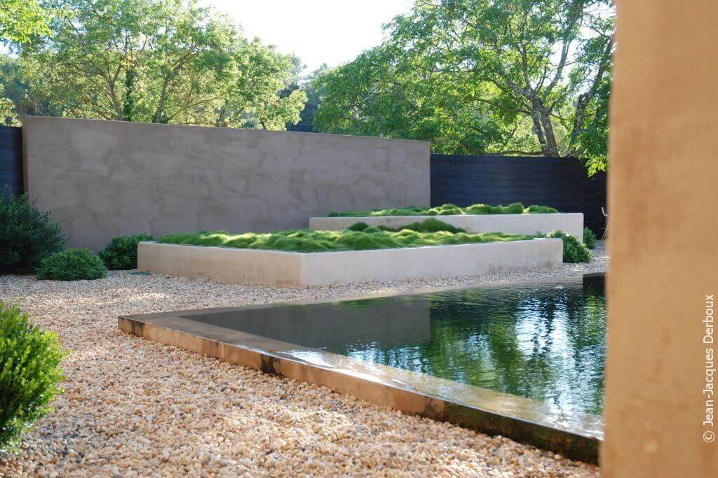 Piscine biologique à débordement, eau effet miroir, grande jardinière maçonnée plantée de zoysia, gravier.