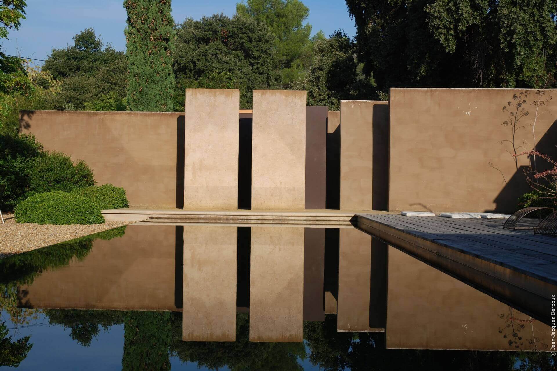 Baignade biologique, mur enduit chaux et pigment naturel, piscine à débordement effet miroir.