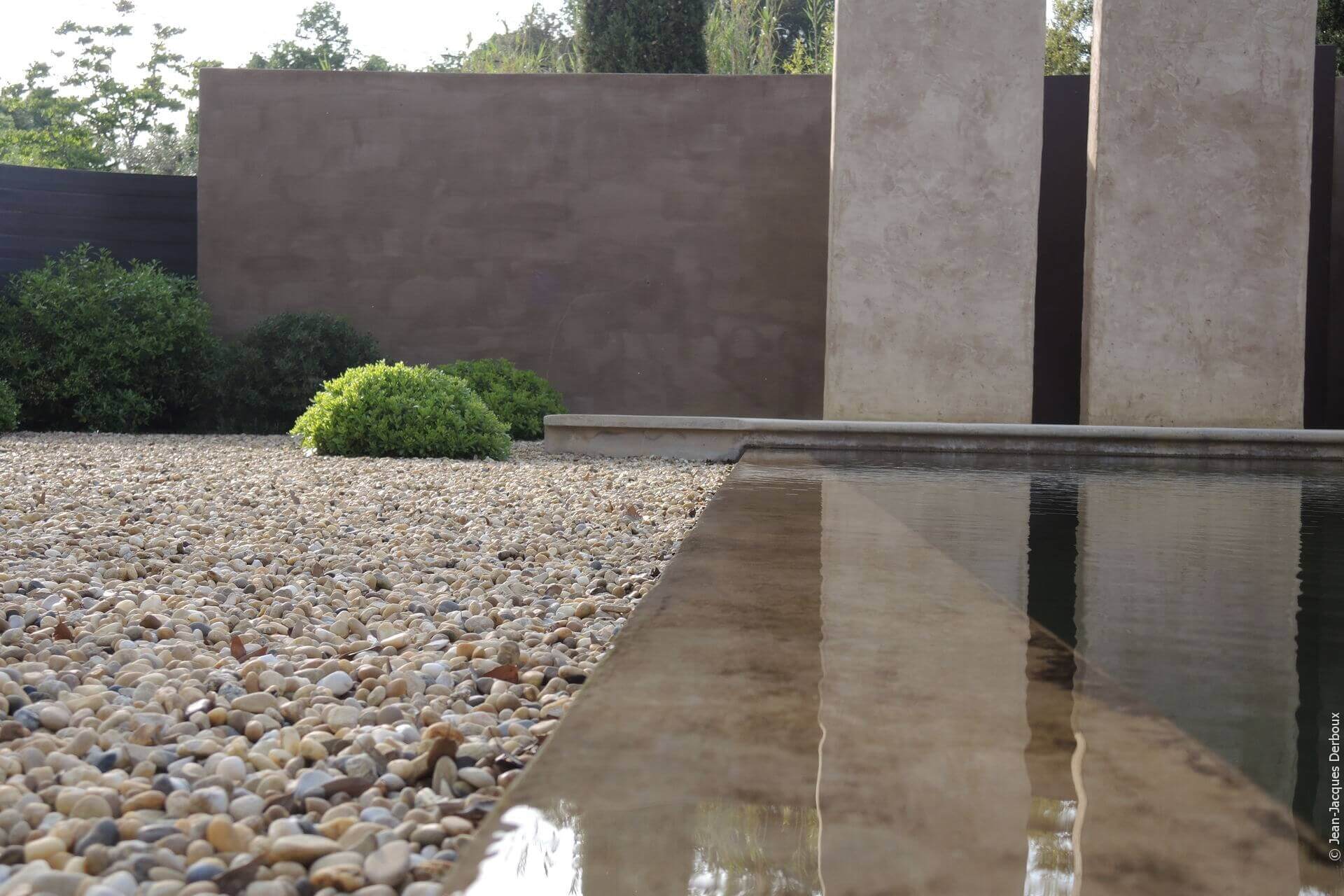 Jardin épuré, jardin contemporain, piscine biologique, piscine à débordement, gravier, mur enduit pigment naturel.