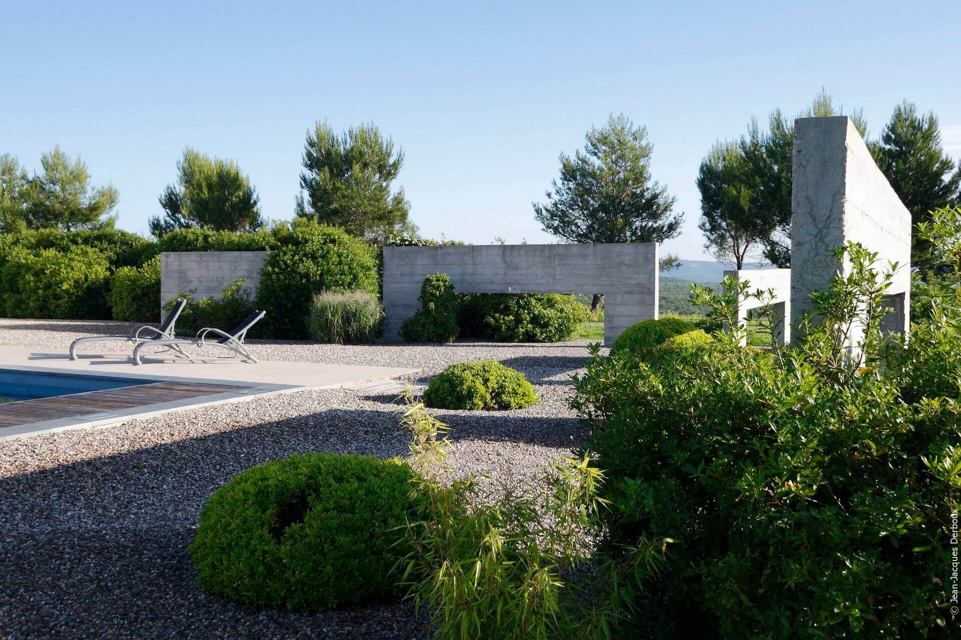 Jardin contemporain autour de la piscine, structure béton décorative, jardin sur gravier, jardin sec, bain de soleil, pittosporum tobira nana, végétaux taillés en topiaire.