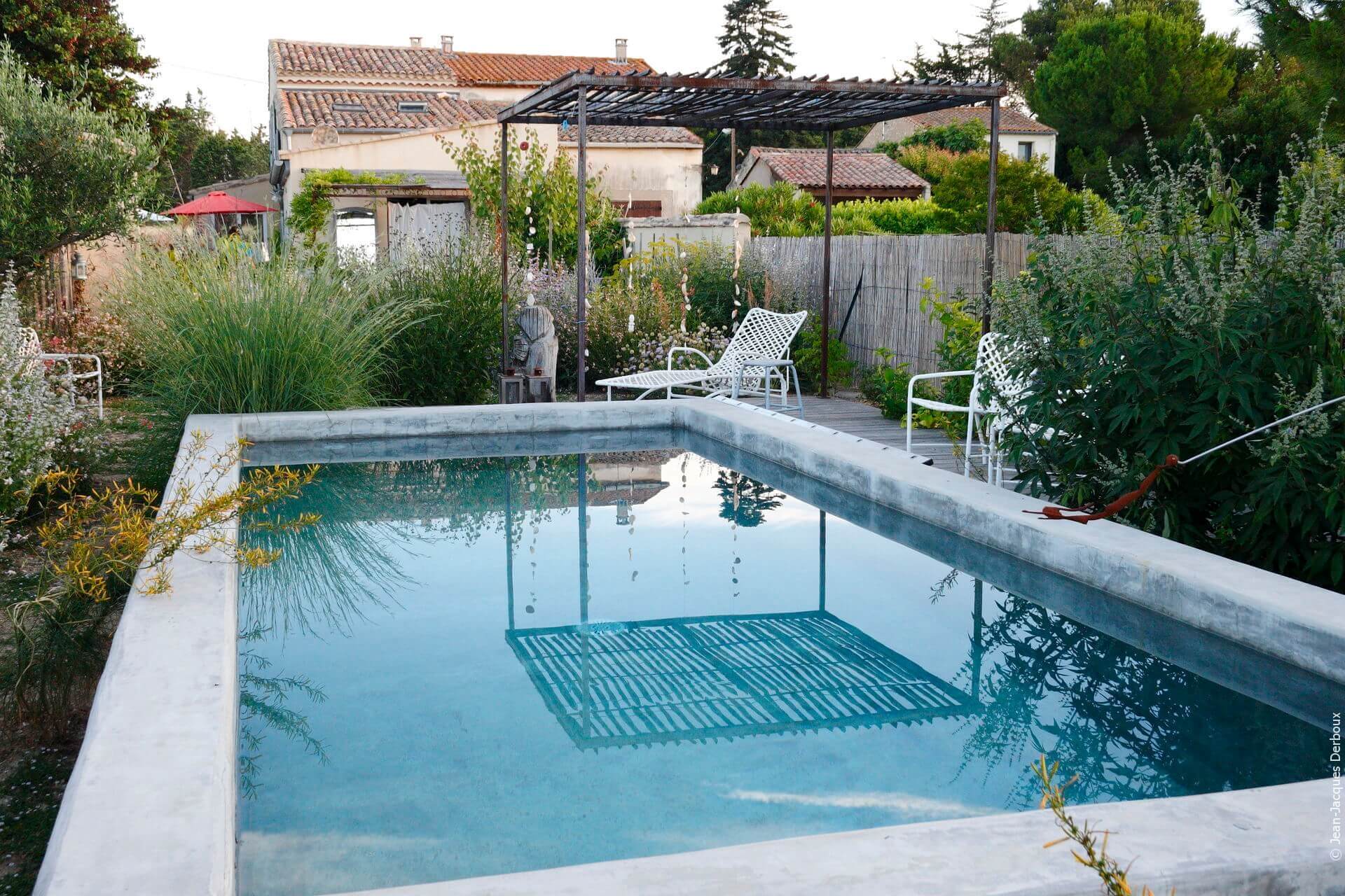 Petite piscine en ciment gris, treille d’ombrage, bain de soleil, reflet dans l’eau, graminée, décoration de jardin.