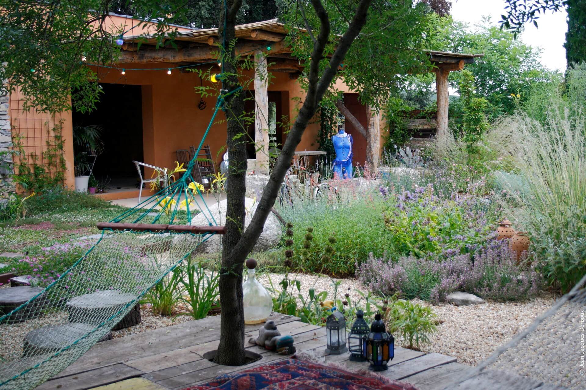 Jardin écologique, jardin sans arrosage, esprit bohème, hamac, terrasse, gravier, terrasse bois, lanterne, décoration de jardin.